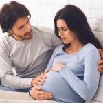 A father and mother holding her belly.