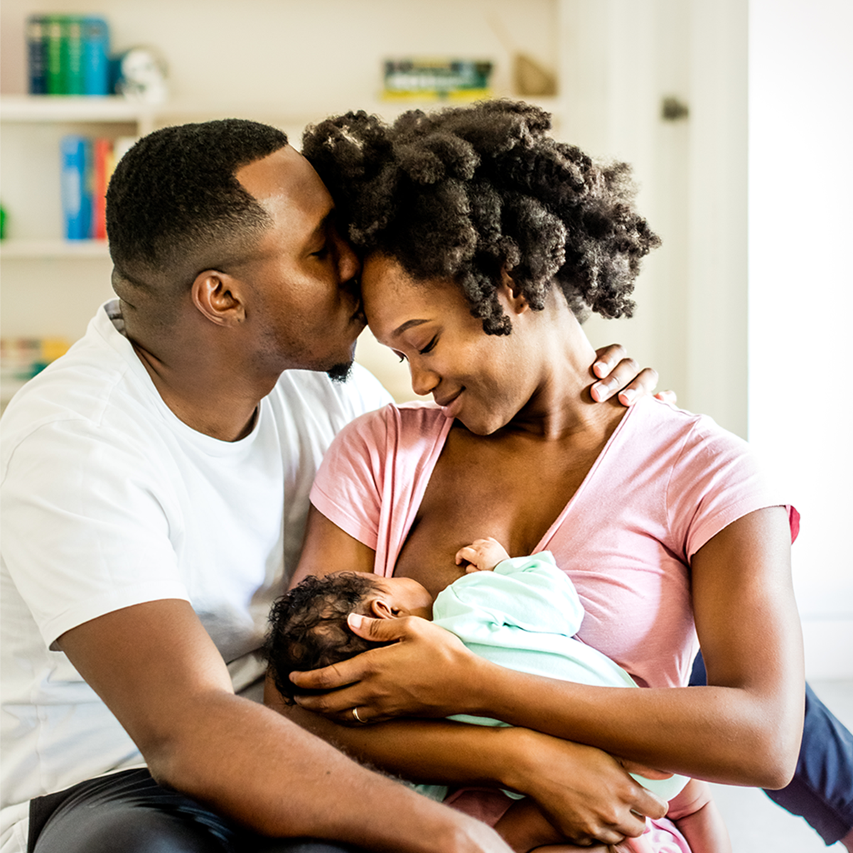 A mother and father embracing while the mother breastfeeds. 