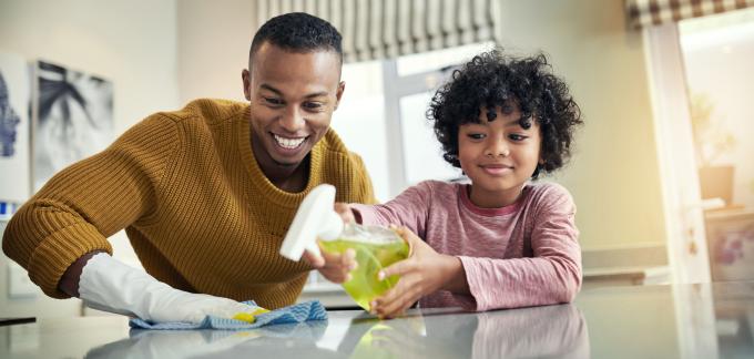 Un padre y una hija limpian una mesa.