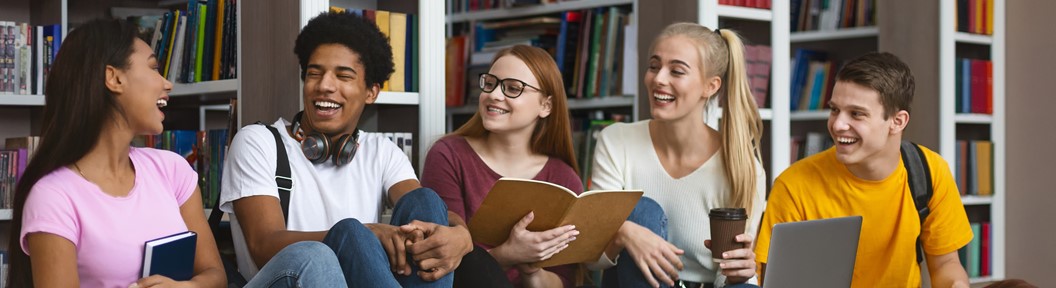 Adolescents in a library talking ang laughing together.