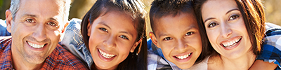 A mother and a father smile at a camera with their son and daughter.